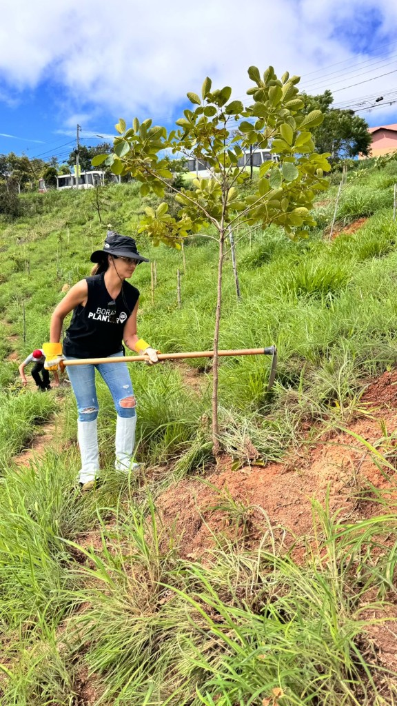 Voluntária do Bora Plantar fazendo o coroamento de uma muda com enxada