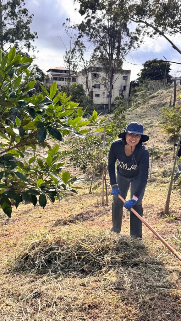 Voluntária do Bora Plantar rastelando palha seca para reduzir o risco de incêndio